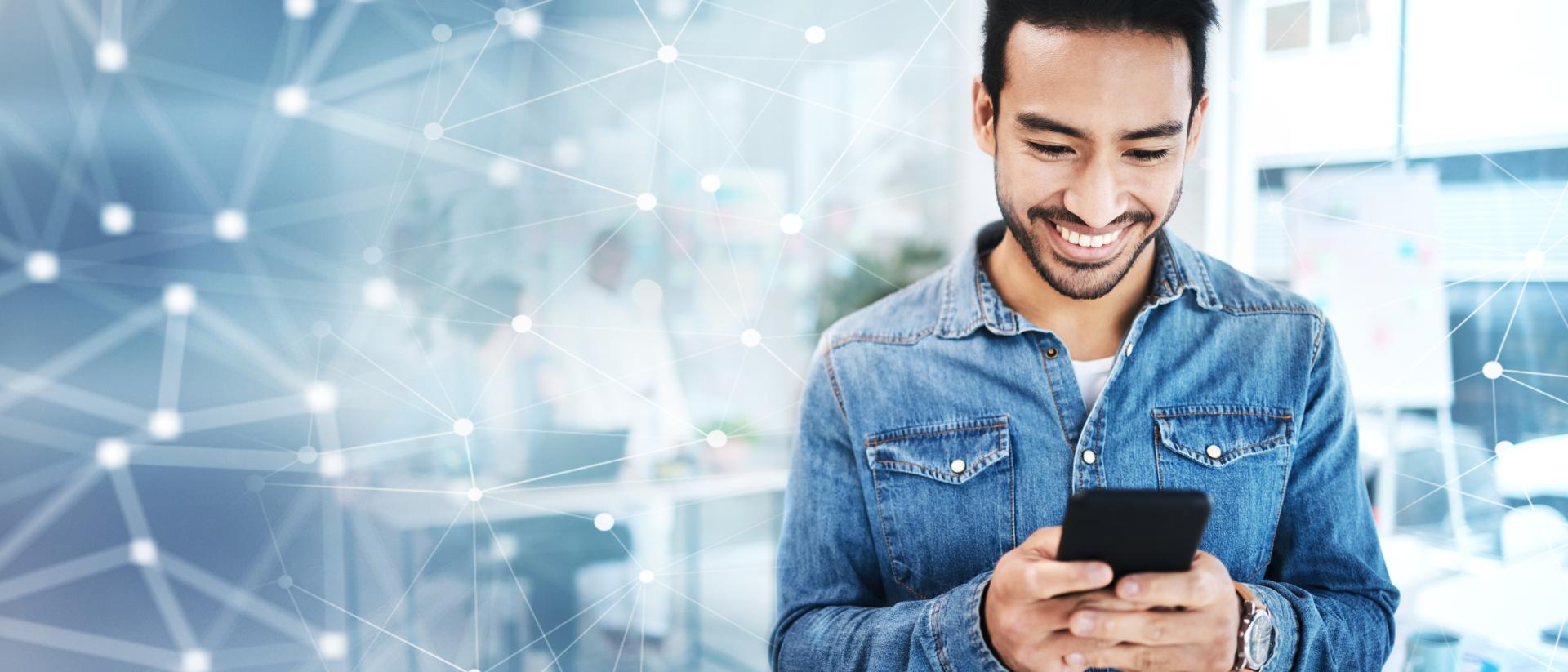 In his office, a man smiling with his mobile phone in his hand
