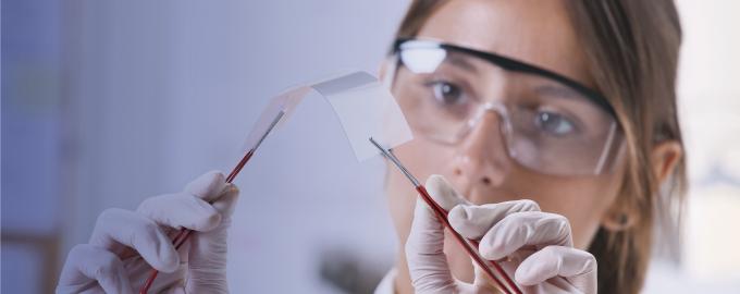 A woman works in a laboratory wearing protective goggles