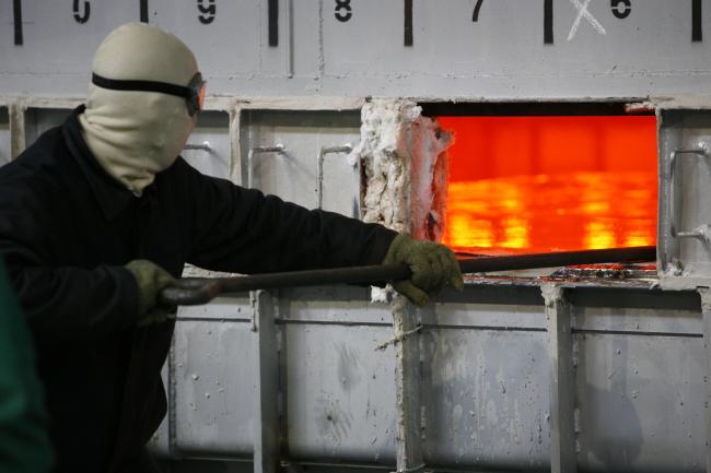a man wearing a protective mask, goggles and gloves works in an AGC factory