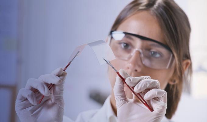 A woman works in a laboratory wearing protective goggles